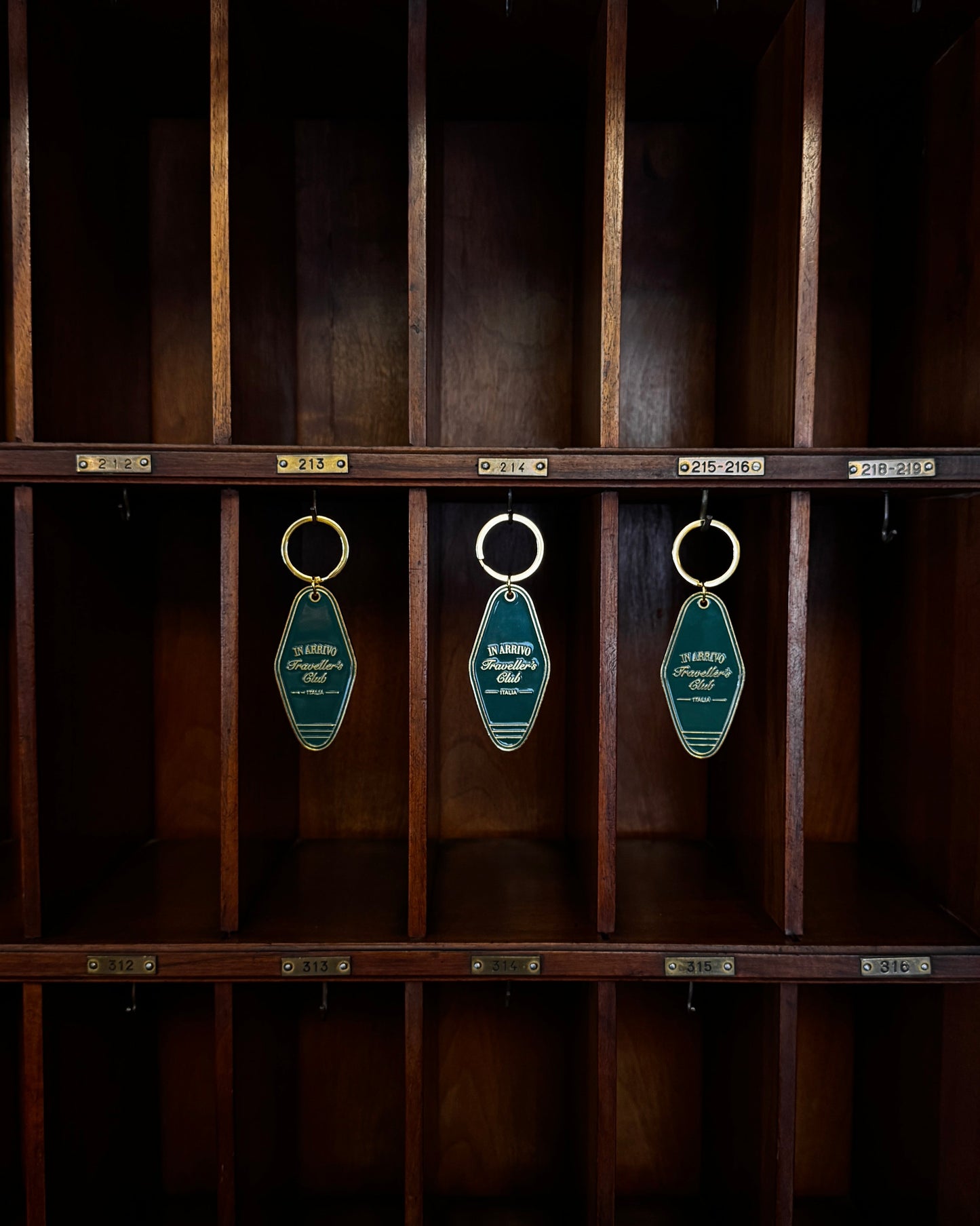 Wooden cabinet with green keychains hanging from hooks on a dark background