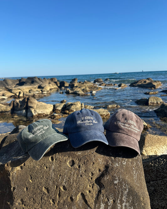 Three caps on a rock by the ocean with clear blue sky  in arrivo italian lifestyle brand